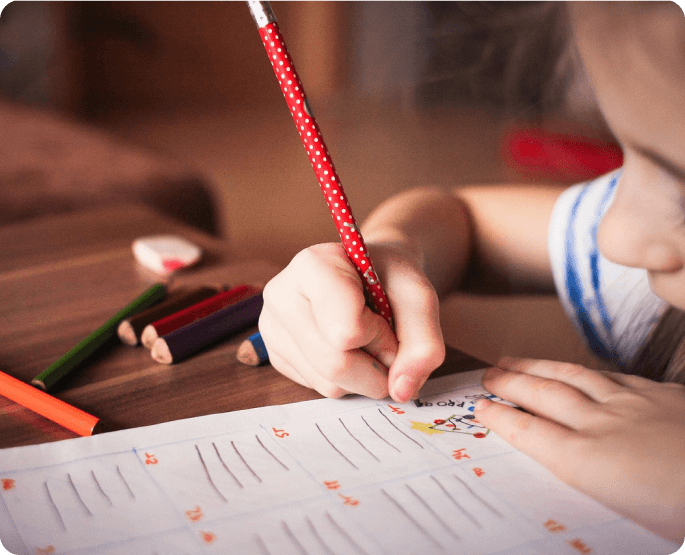 A child is writing on paper with a pencil.