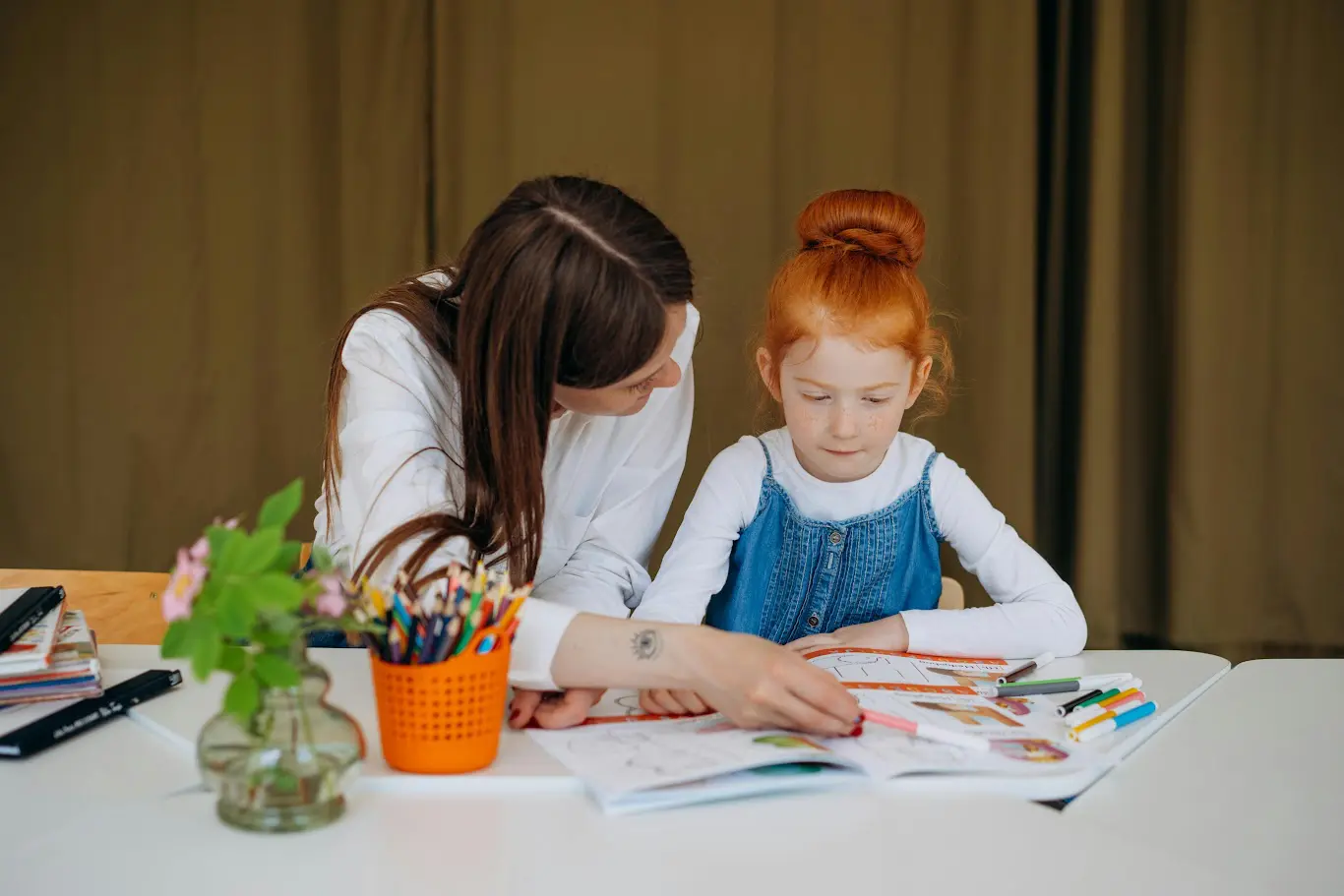 A woman and girl sitting at table with papers.